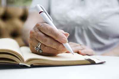 senior holding pen in hand and writing in journal